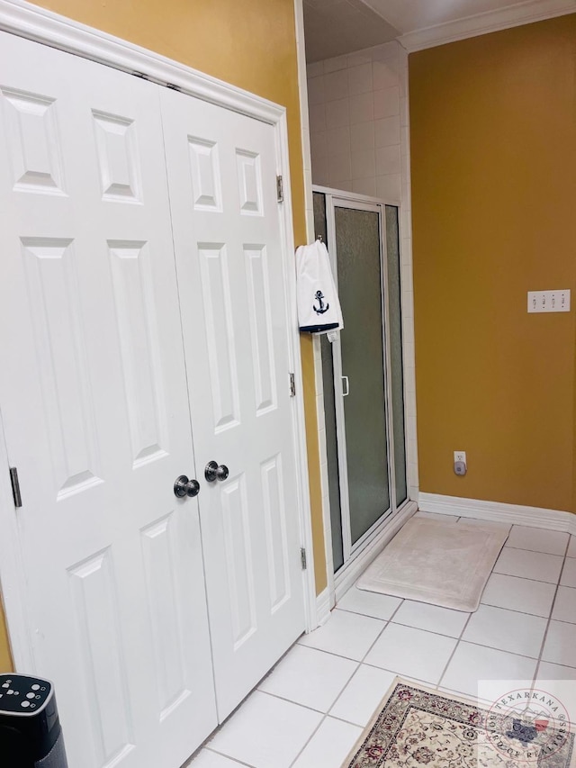 bathroom with tile patterned floors, a shower with door, and ornamental molding