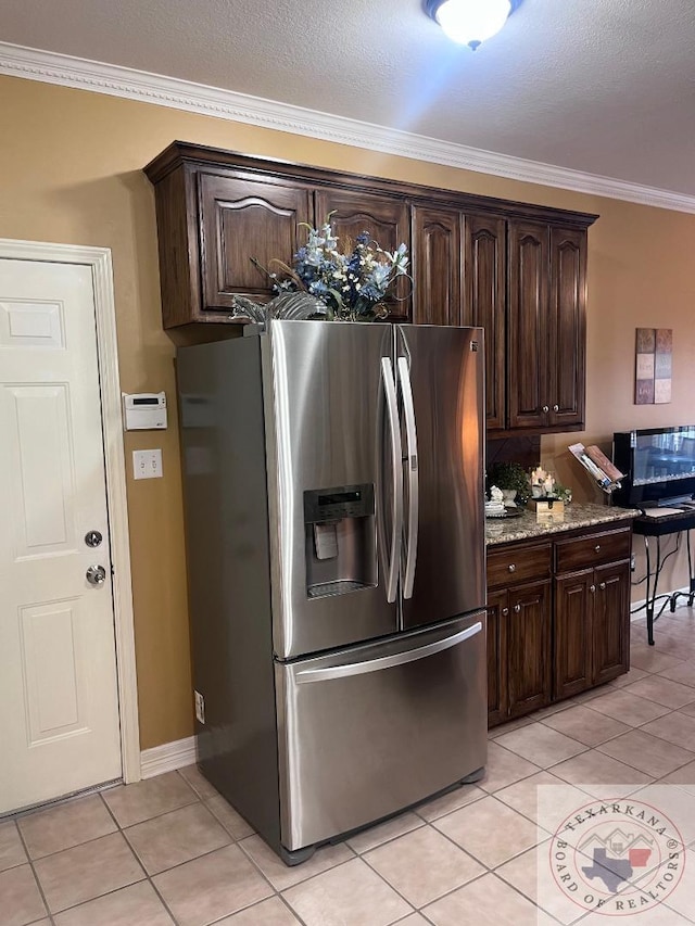 kitchen featuring dark brown cabinets, stainless steel fridge with ice dispenser, light tile patterned floors, light stone counters, and ornamental molding