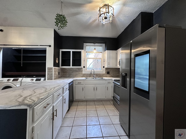 kitchen featuring light tile patterned floors, white cabinets, sink, washing machine and dryer, and stainless steel appliances