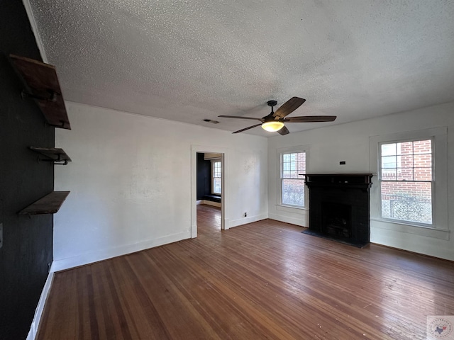 unfurnished living room featuring dark wood-type flooring, a textured ceiling, and ceiling fan