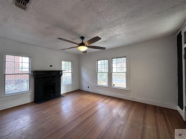 unfurnished living room featuring hardwood / wood-style floors, a textured ceiling, a healthy amount of sunlight, and a fireplace