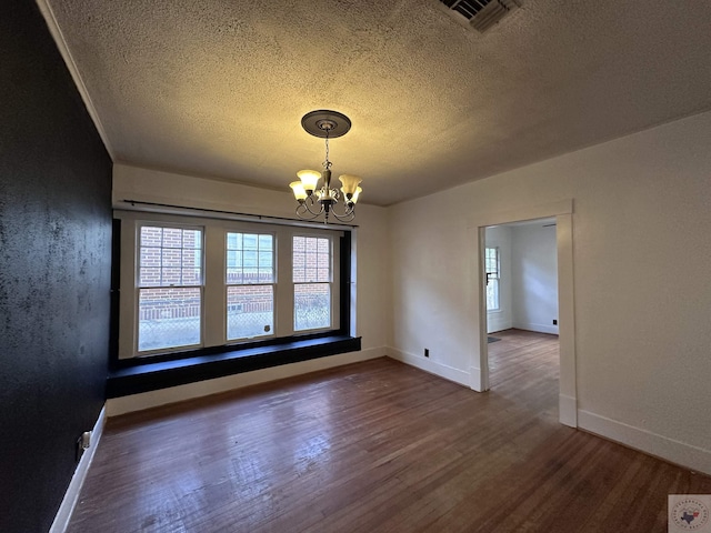 unfurnished dining area with dark wood-type flooring, a textured ceiling, and a chandelier