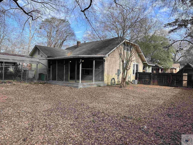 rear view of house with a sunroom, central AC, and a carport