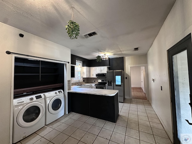 kitchen with white cabinets, washing machine and dryer, stainless steel appliances, kitchen peninsula, and light tile patterned floors