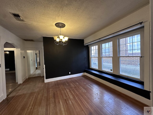 unfurnished dining area featuring a notable chandelier, hardwood / wood-style flooring, and a textured ceiling