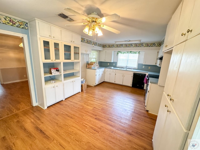 kitchen with white cabinets, black dishwasher, stove, and light wood-type flooring