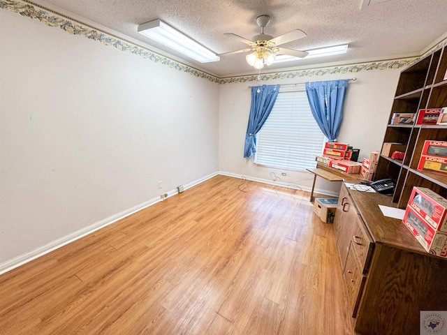 unfurnished office featuring light wood-type flooring, ceiling fan, and a textured ceiling