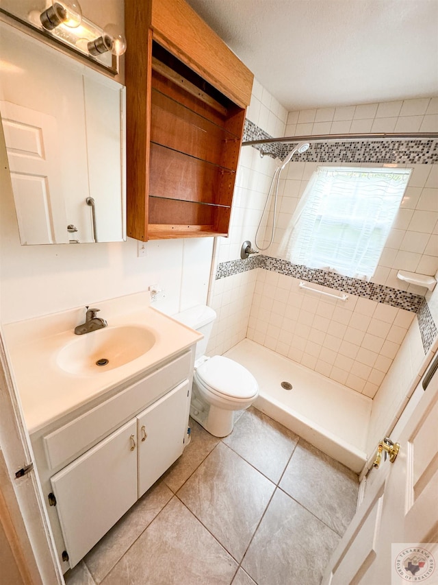 bathroom featuring a tile shower, toilet, tile patterned flooring, and vanity