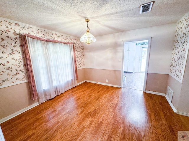 empty room with hardwood / wood-style flooring and a textured ceiling