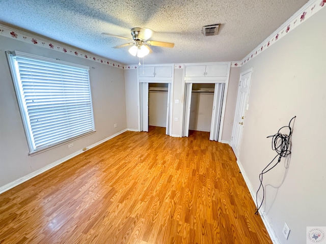 unfurnished bedroom featuring ceiling fan, light hardwood / wood-style floors, a textured ceiling, and multiple windows