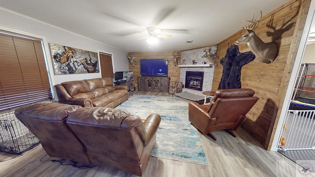 living room featuring ceiling fan, a fireplace, and light hardwood / wood-style flooring