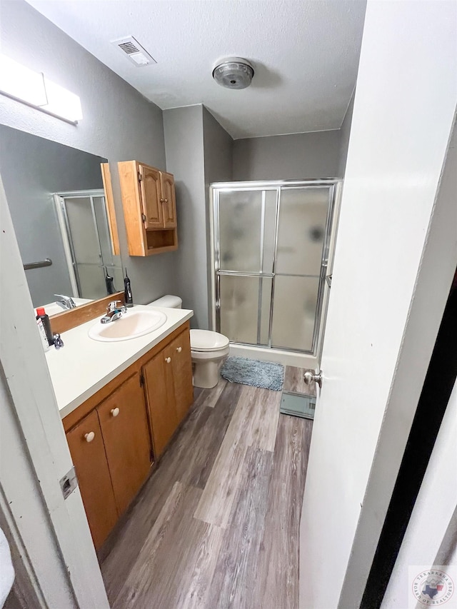 bathroom with walk in shower, toilet, wood-type flooring, a textured ceiling, and vanity