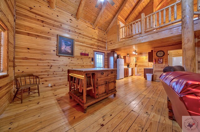 bedroom featuring wood ceiling, white refrigerator, wood walls, and beamed ceiling