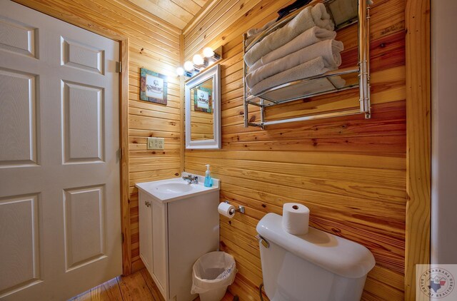 bathroom featuring wooden walls, toilet, and vanity