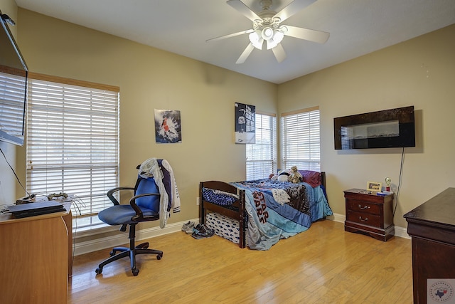 bedroom with multiple windows, light wood-type flooring, and baseboards