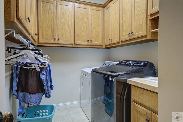 laundry room featuring tile patterned floors, cabinet space, baseboards, and washing machine and clothes dryer