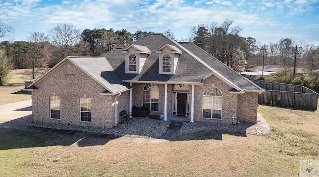 view of front of property featuring a front yard, brick siding, and a shingled roof