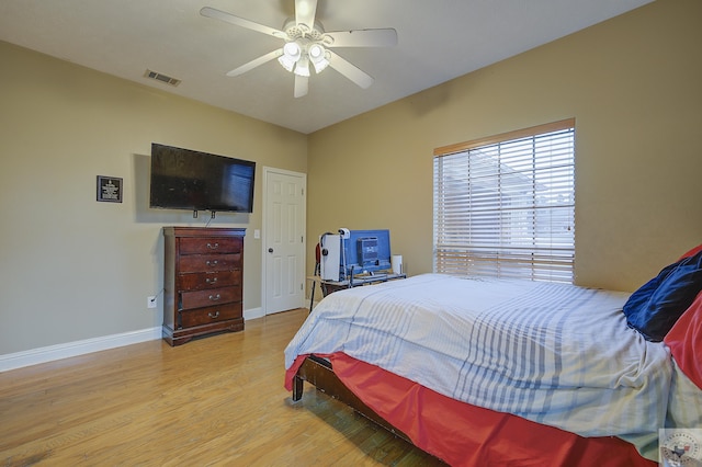 bedroom with ceiling fan, visible vents, baseboards, and wood finished floors