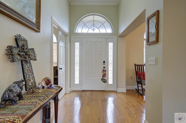 foyer featuring crown molding, baseboards, and light wood finished floors