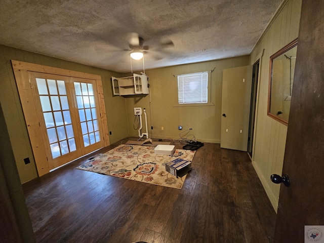 interior space featuring dark wood-type flooring, a textured ceiling, a wall unit AC, and wooden walls