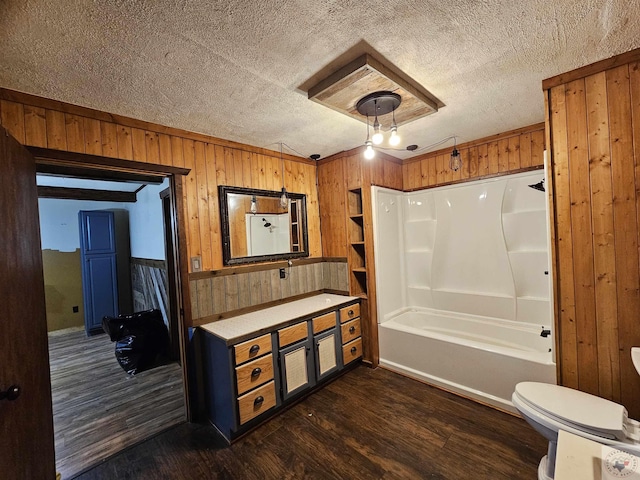 full bathroom with wood-type flooring, vanity, shower / washtub combination, wooden walls, and toilet