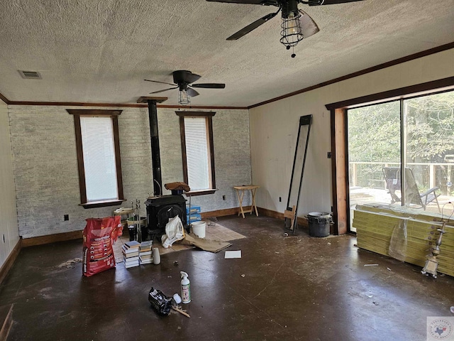 interior space with ceiling fan, a wood stove, a textured ceiling, and crown molding