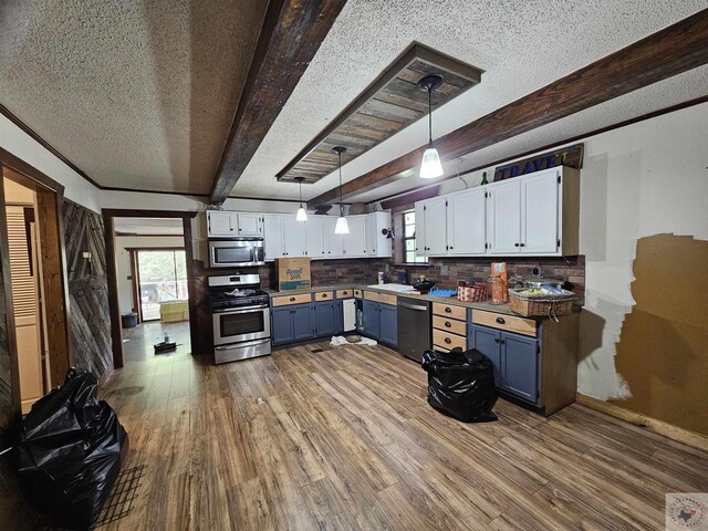 kitchen featuring tasteful backsplash, white cabinetry, beam ceiling, and appliances with stainless steel finishes