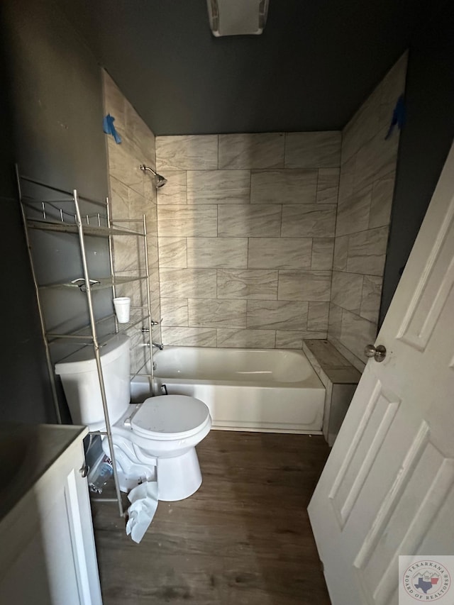 full bathroom featuring vanity, hardwood / wood-style floors, tiled shower / bath combo, and toilet