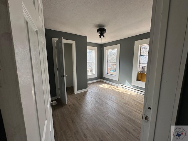 foyer with hardwood / wood-style floors, a textured ceiling, and a baseboard heating unit