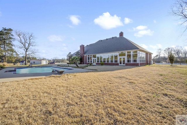 rear view of property featuring french doors, a chimney, a yard, an outdoor pool, and a patio