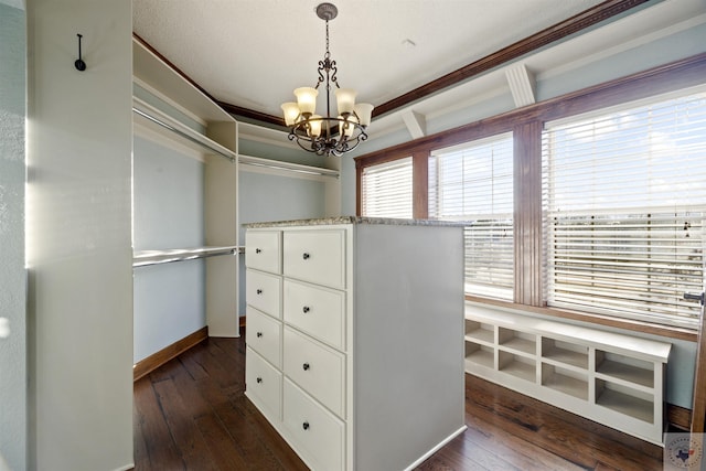 walk in closet featuring dark wood finished floors and a notable chandelier