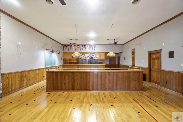 kitchen with a wainscoted wall, light wood-style flooring, and a ceiling fan