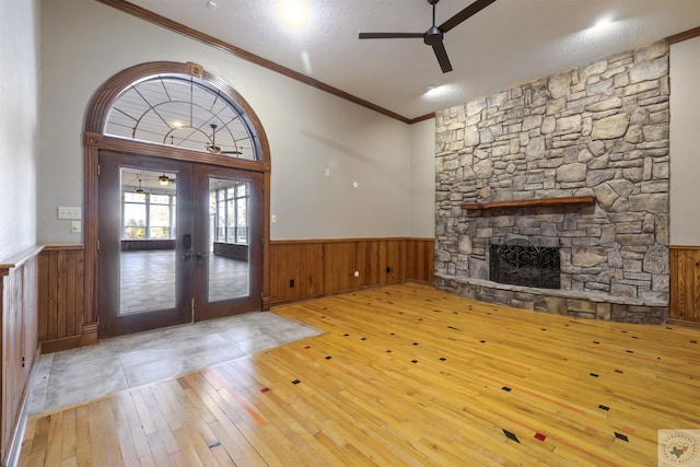 foyer featuring a wainscoted wall, a ceiling fan, hardwood / wood-style flooring, french doors, and a fireplace