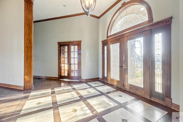 foyer entrance featuring crown molding, french doors, baseboards, and a wealth of natural light