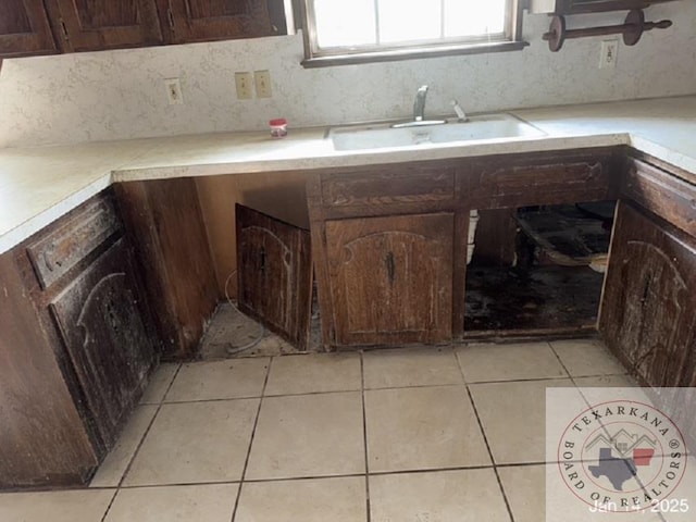 kitchen featuring sink, backsplash, dark brown cabinets, and light tile patterned flooring