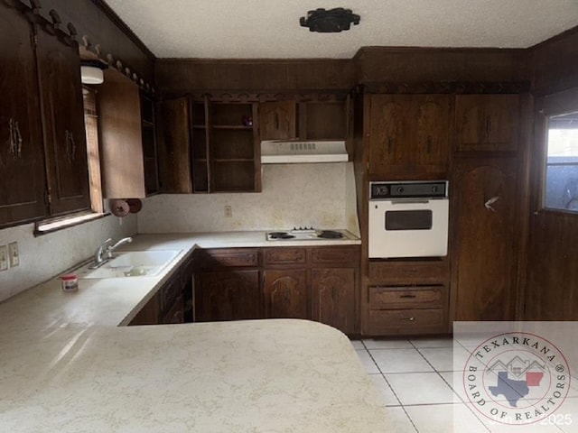 kitchen with sink, white appliances, a textured ceiling, and dark brown cabinetry