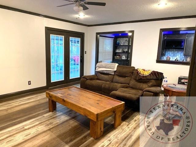 living room with ceiling fan, ornamental molding, light hardwood / wood-style floors, and a textured ceiling