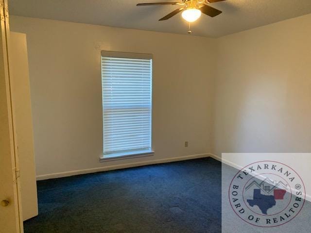 empty room with ceiling fan and dark colored carpet