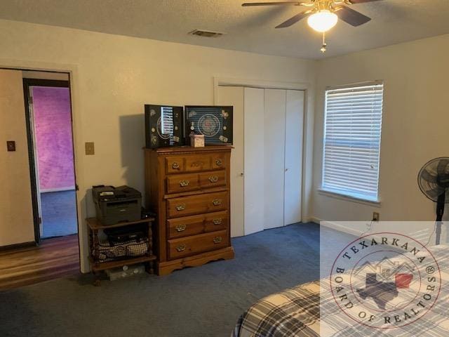 carpeted bedroom with ceiling fan, a textured ceiling, and a closet