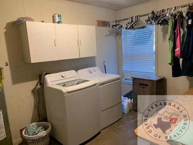 clothes washing area featuring cabinets and washer and clothes dryer