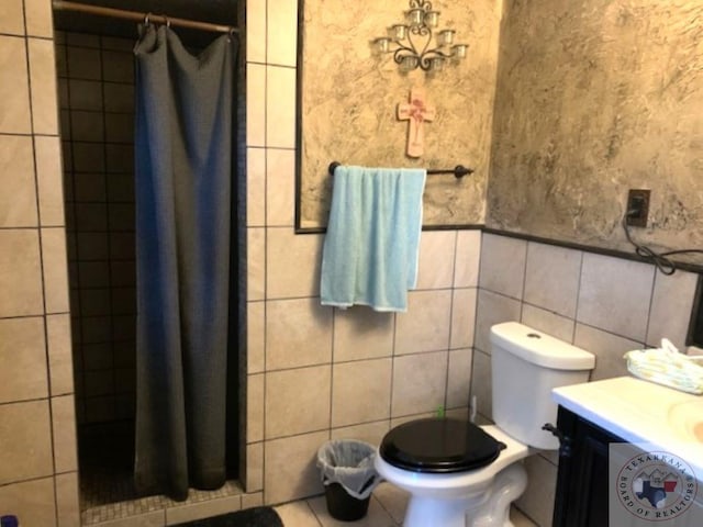 bathroom featuring toilet, vanity, and tile walls