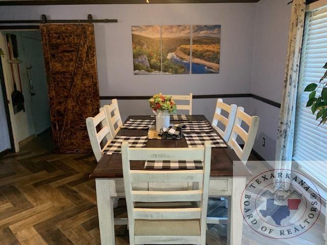 dining space with a barn door and dark parquet flooring