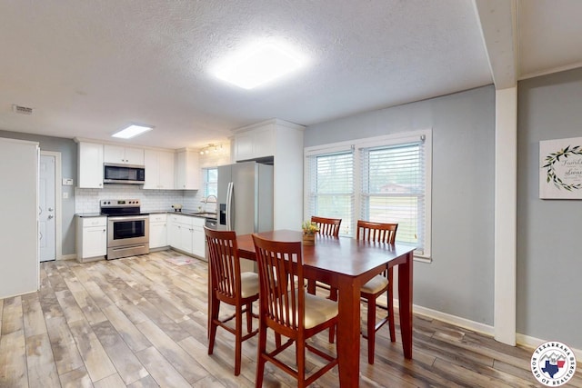 2101 N Fm 2148, Texarkana, TX 75501 - dining space featuring light wood finished floors, a textured ceiling, and baseboards