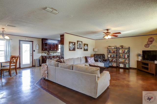 living room with ceiling fan with notable chandelier and a textured ceiling