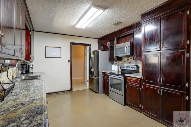 kitchen with visible vents, a sink, stainless steel appliances, a textured ceiling, and backsplash