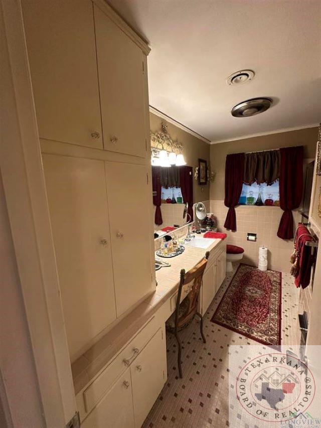 bathroom with vanity, toilet, and crown molding