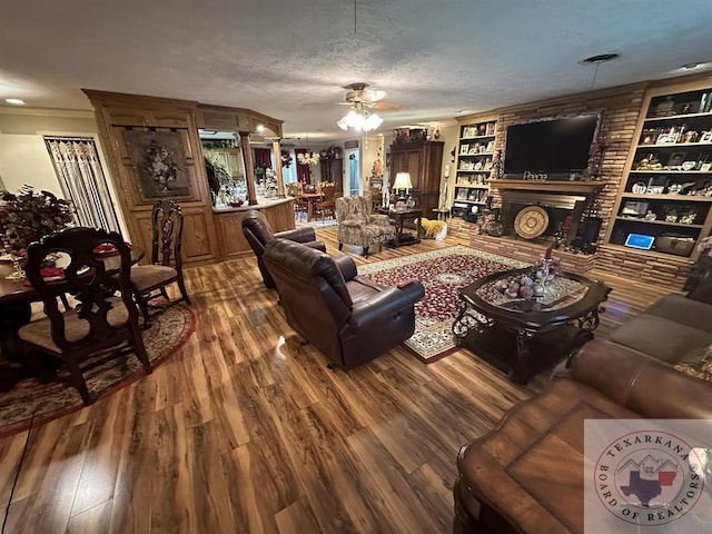 living room featuring built in shelves, hardwood / wood-style floors, a textured ceiling, and a fireplace