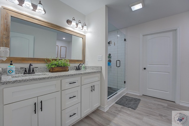 bathroom featuring wood-type flooring, a shower with door, and vanity