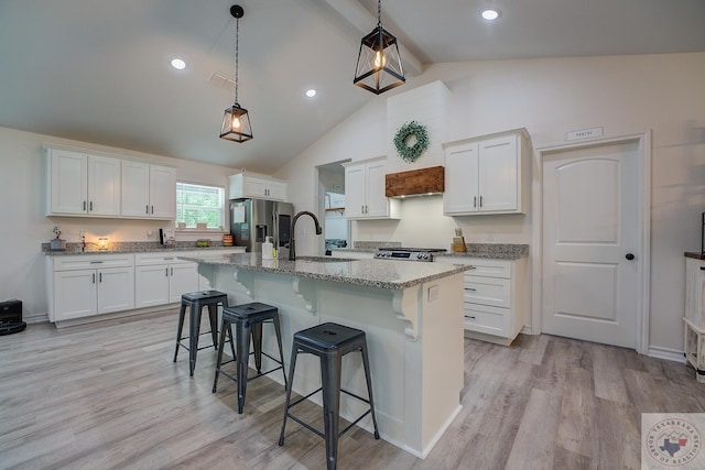 kitchen with a center island with sink, white cabinets, stainless steel fridge with ice dispenser, and hanging light fixtures