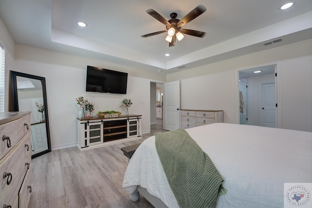 bedroom featuring ceiling fan, a raised ceiling, and light hardwood / wood-style floors